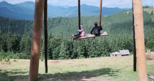 Children sitting on traditional wooden swing — Stock Video