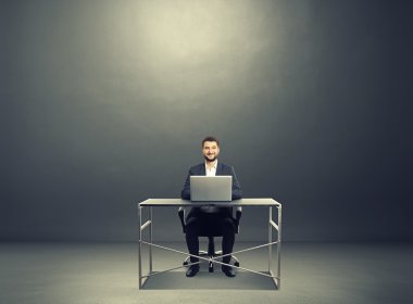 laptop ile masada oturan gülen adam