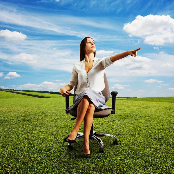 Woman sitting on the chair and pointing — Stock Photo, Image