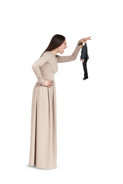 Angry young woman holding small man — Stock Photo, Image