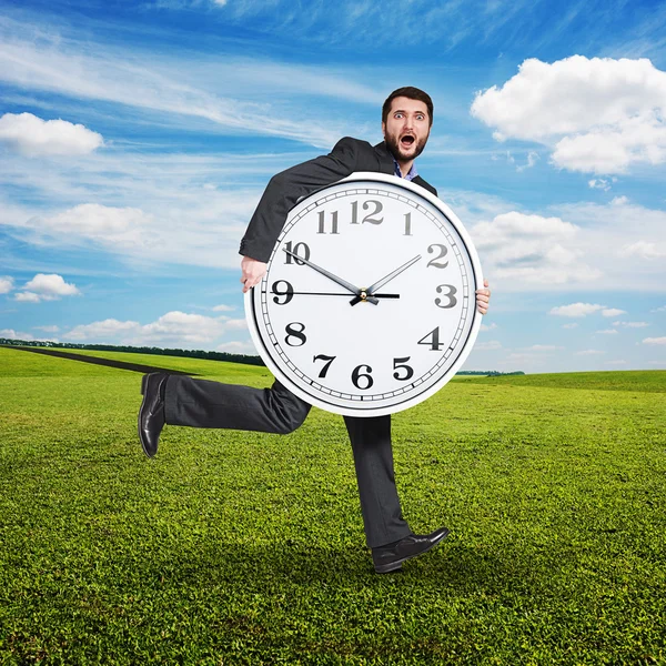 Hombre asustado sosteniendo gran reloj blanco — Foto de Stock