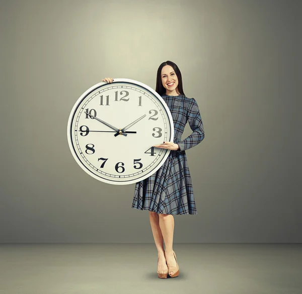 Збуджена молода жінка тримає великий годинник — стокове фото
