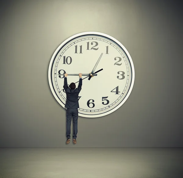 Man hanging on big clock hand - Stock Image - Everypixel