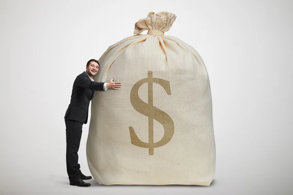 Happy man embracing big bag with money — Stock Photo, Image