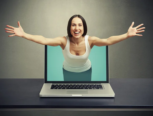 Skrattande kvinna kommer ut från laptop — Stockfoto