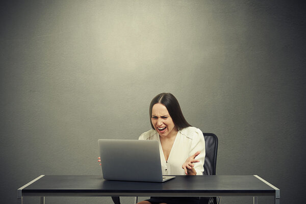 сердитая деловая женщина смотрит на ноутбук
