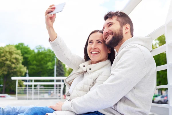 Coppia seduta e scattare un selfie — Foto Stock