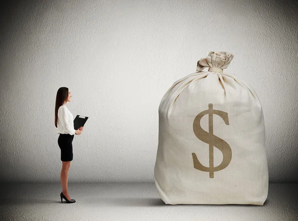 Женщина смотрит на большую денежную сумку — стоковое фото
