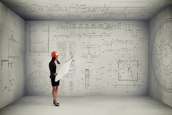 Woman with blueprint in empty room — Stock Photo, Image