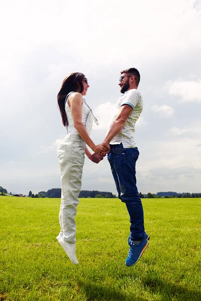 Couple jumping on the green field — Stock Photo, Image