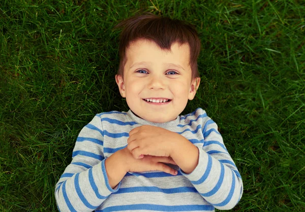 Excited little boy lying on the green grass — Stock Photo, Image