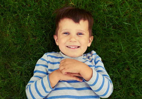 Excité petit garçon couché sur l'herbe verte — Photo