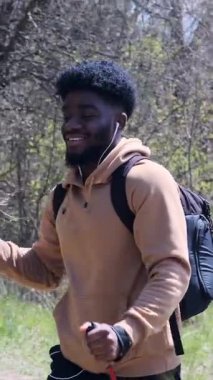 Yetişkin bir adam, parktaki yürüyüş direkleri ile ağır çekimde kuzeye yürüme pratiği yapar..