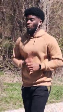 Yetişkin bir adam park yolu boyunca yavaş çekimde koşar, yan açıdan yakalanır..