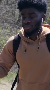 Yetişkin bir adam, bir parkta yürüyüş direkleri ile yavaş çekimde kuzeye yürüme pratiği yapar..