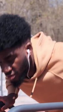 Yetişkin bir adam, yan taraftan çekilen metal parmaklıklara eğik şınav çeker..