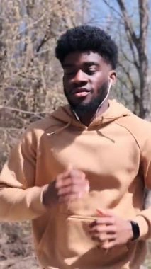 Yetişkin bir adam, park yolu boyunca ağır çekimde koşar, ön taraftan çekilir..