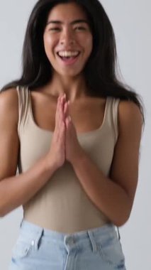 Heyecanlı genç bir kadının portresi ağır çekimde alkışlıyor ve gülümsüyor. O, bir stüdyoda sevinçle kutlar. Beyaz arkaplanda izole.