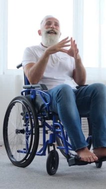 Tekerlekli sandalyedeki mutlu son sınıf öğrencisi, kadın bakıcısıyla gülüp şakalaşıyor. Kız onu itiyor, o da kendini ileri itiyor. Evde bakım. Dikey video.