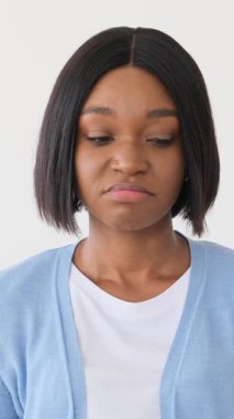 Şüpheci genç bir Afro-Amerikan kadının portresi bıkkın ve hayal kırıklığına uğramış görünüyor. Kaşlarını çatıyor ve beyaz arka planda izole edilmiş olumsuz bir tepki gösteriyor..