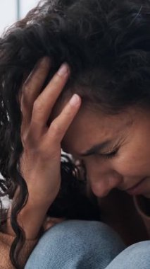 Üzgün genç bir kadın ağlıyor ve yüzünü eliyle kapatıyor. Depresyondaki kadın ümitsiz, kederli ya da evde duygusal acı çeken..