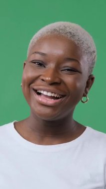 Mutlu, Afro-Amerikan bir kadının portresi. El çırpıyor ve gülümsüyor. Yeşil arka planda heyecanlı ve neşeli görünüyor..