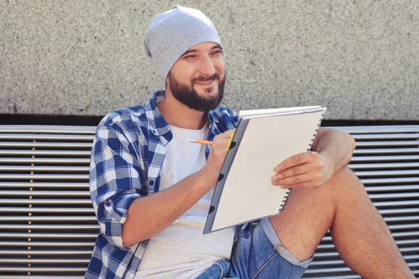 Glada skäggig man sitter på bänken — Stockfoto