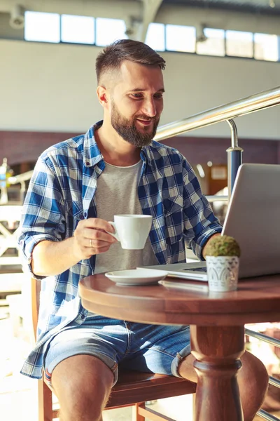 コーヒーを飲みながら陽気な若い成人男性 — ストック写真