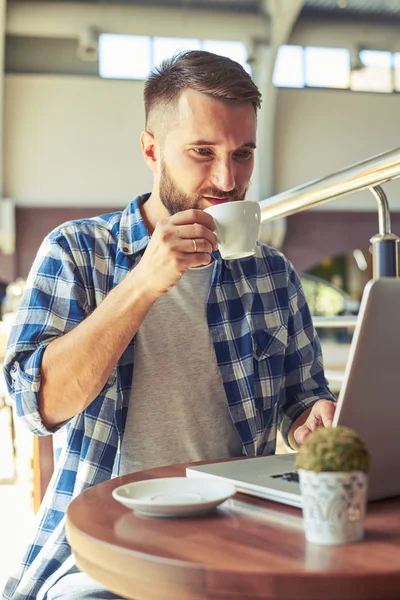 コーヒーを飲みながらのラップトップで働く男 — ストック写真