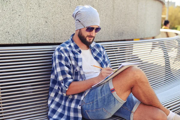 Man zittend op een bankje en schrijven — Stockfoto