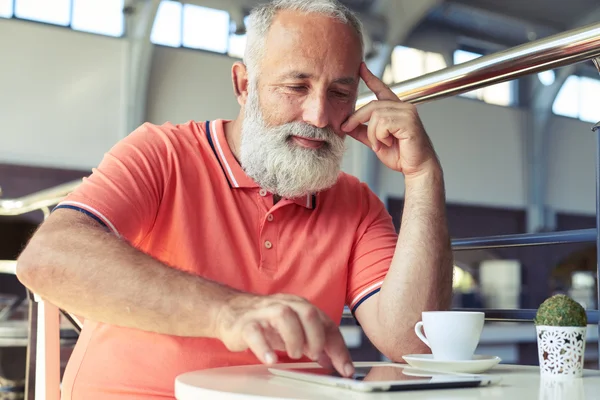Старший чоловік використовує планшетний ПК в кафе — стокове фото