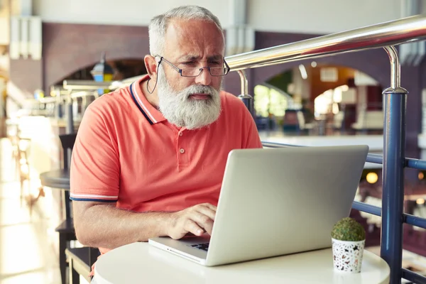 Ernsthafter Senior arbeitet mit Laptop — Stockfoto