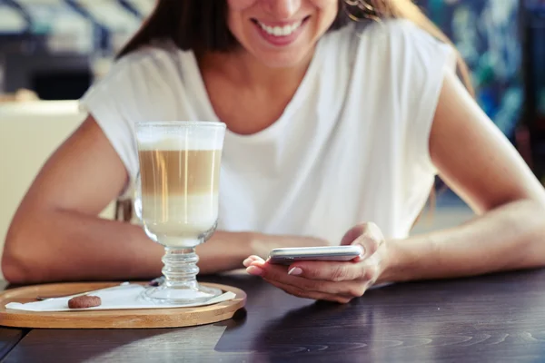 Женщина сидит в кафе со смартфоном — стоковое фото