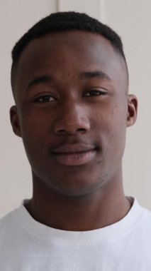 Dikey video. Kameraya sakin bir ifadeyle bakan Afrikalı genç bir Amerikalı 'nın yakın plan portresi..