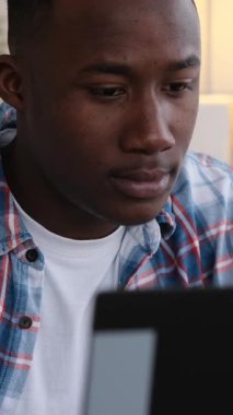 Evde dizüstü bilgisayar üzerinde çalışan Afrikalı genç bir Amerikalı. Dikey video.