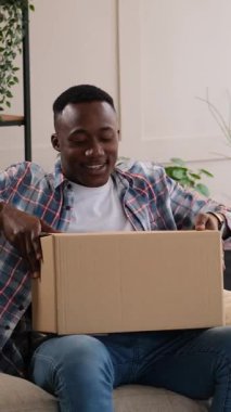 Bir paketi açan hayal kırıklığına uğramış bir adamın dikey videosu. Evdeki kanepede otururken çevrimiçi bir siparişten yanlış bir şey aldığı için hayal kırıklığına uğradı..