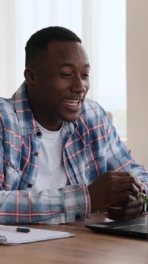 Bilgisayarındaki video görüşmesi sırasında gülen ve konuşan Afro-Amerikan bir adamın dikey videosu. Konuşmanın sonunda el sallıyor..