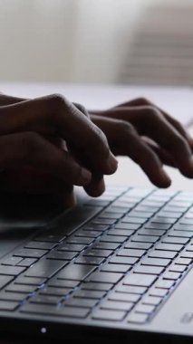 Laptop klavyesine yazı yazan Afrikalı bir Amerikalının yakın çekimi. Dikey video.