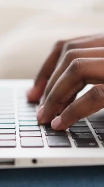 Laptop klavyesine yazı yazan Afrikalı Amerikalı bir kadının yakın çekimi. Dikey video.