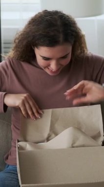 Mutlu genç bir kadın yeni beyaz spor ayakkabılarıyla paketini açıyor. Çevrimiçi alımı için çok heyecanlı. Dikey video.