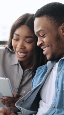 Mutlu genç çift evde dijital tablet kullanıyor. dikey video