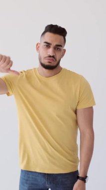 Memnuniyetsiz bir adam, beyaz arka planda izole edilmiş bir şekilde baş parmak hareketi yapıyor. Dikey video.
