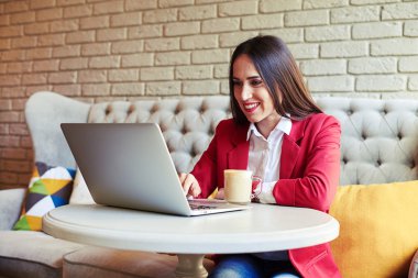 Kafede dizüstü bilgisayar kullanan genç bir kadın