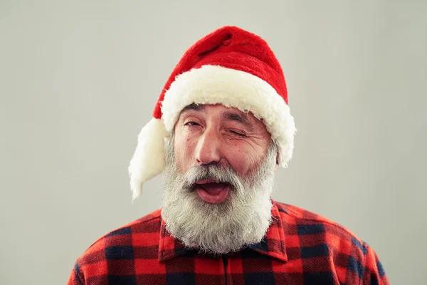 Senior mit Weihnachtsmütze blickt in die Kamera und zwinkert — Stockfoto