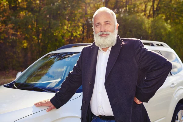 Sonriente hombre mayor cerca de su coche blanco al aire libre — Foto de Stock