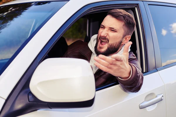 Young man shouting from the window of his car — Stock Photo, Image