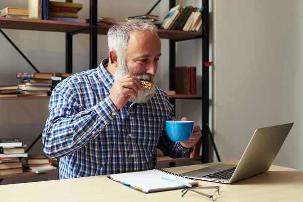 Fröhlicher älterer Herr mit Plätzchen und Kaffee — Stockfoto