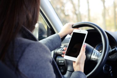 Smartphone kullanarak ve bir arabayı kullanan kadın