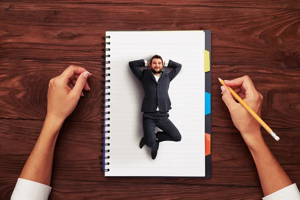 Small man resting on big notepad — Stock Photo, Image