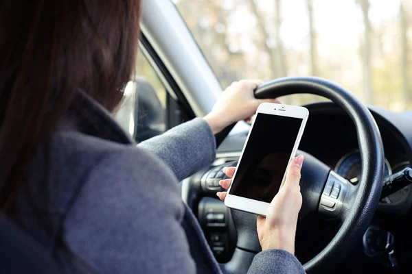 Femme utilisant un smartphone et conduisant une voiture — Photo